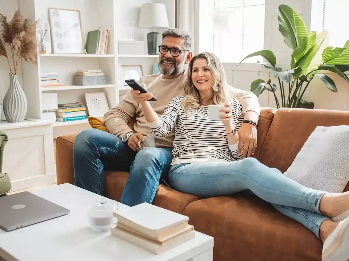 an older couple watching tv at home on their couch